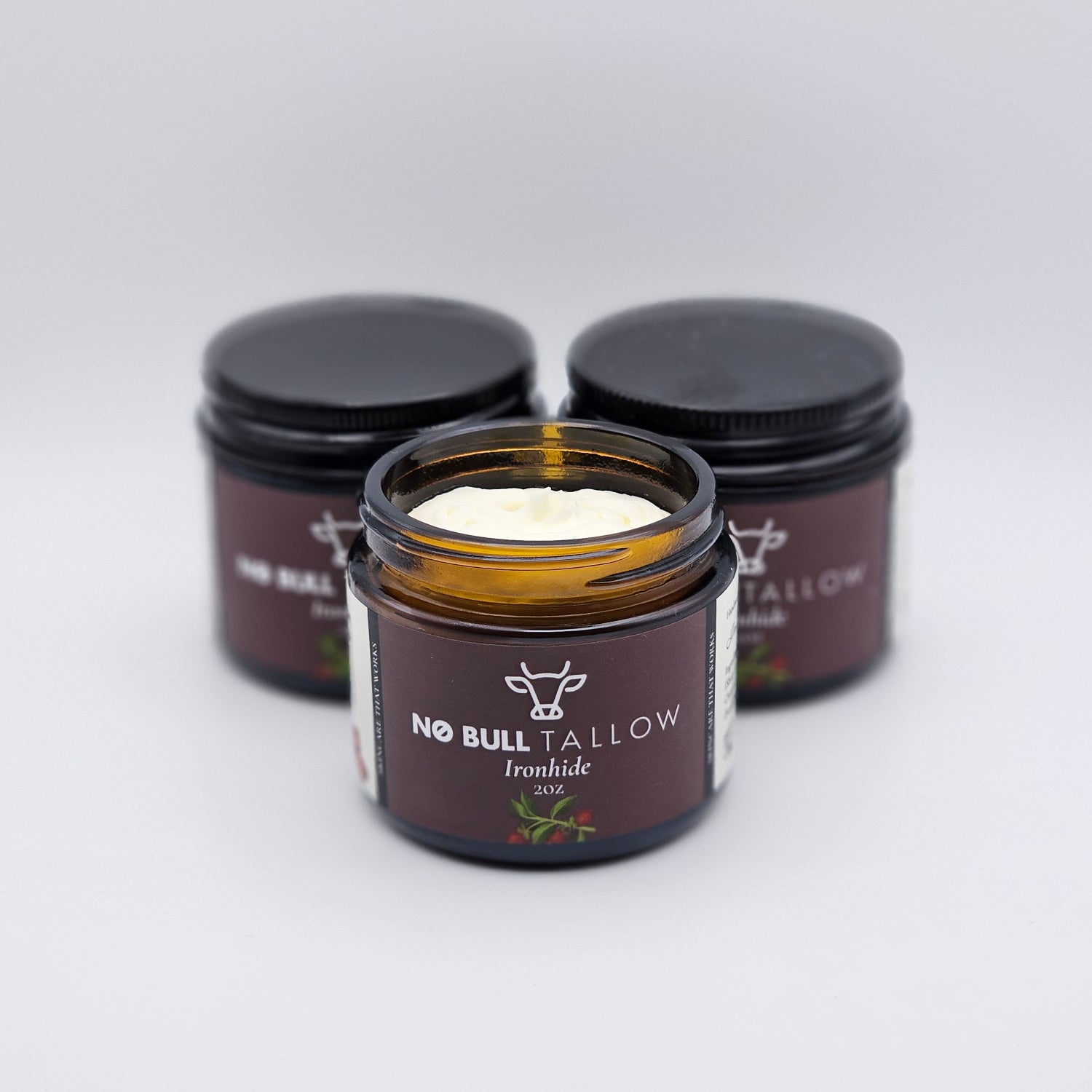 three sxmall jars of Ironhide, natural tallow body butter with brown labels on a white background