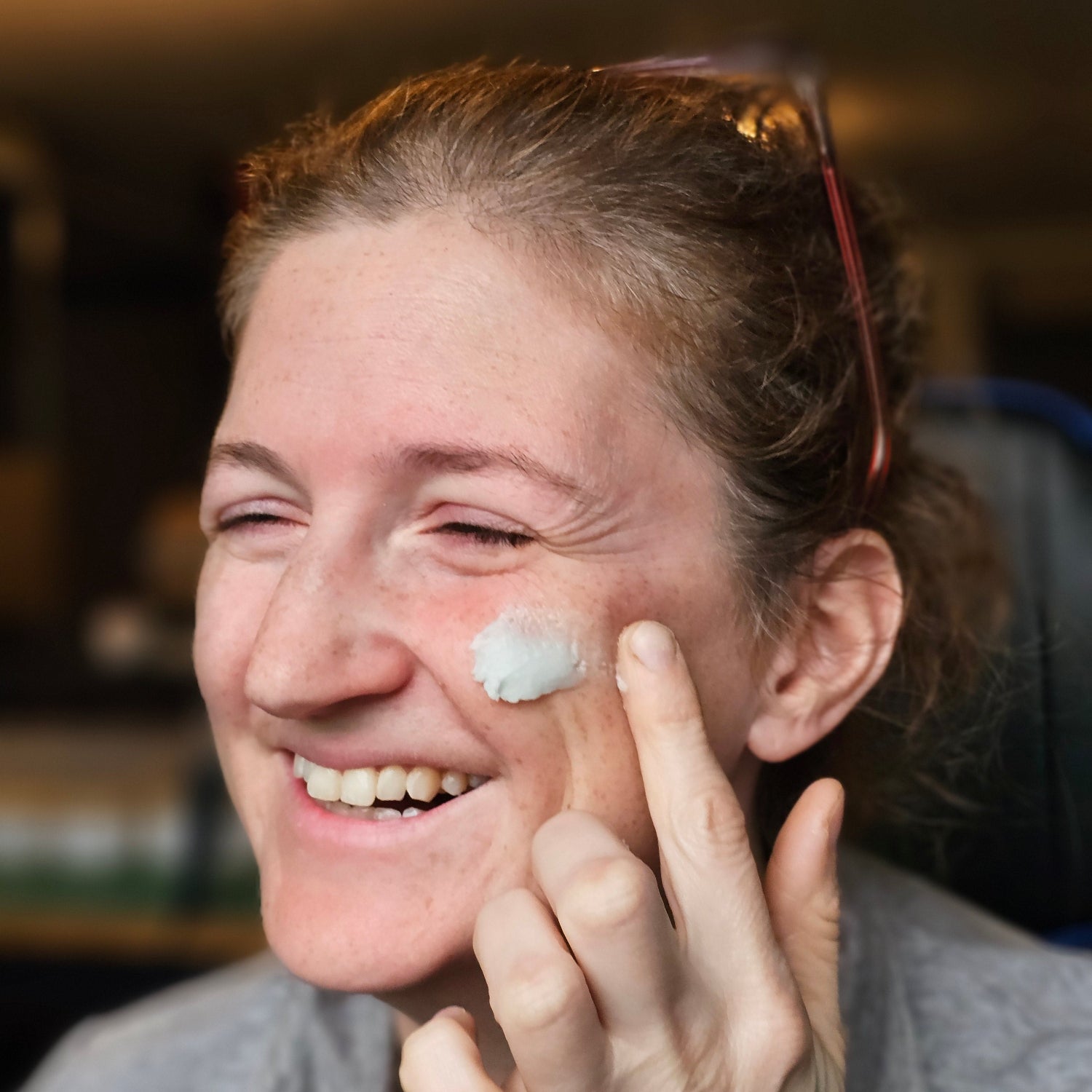 a smiling woman applying cloud cream- natural tallow moisturizer on her face