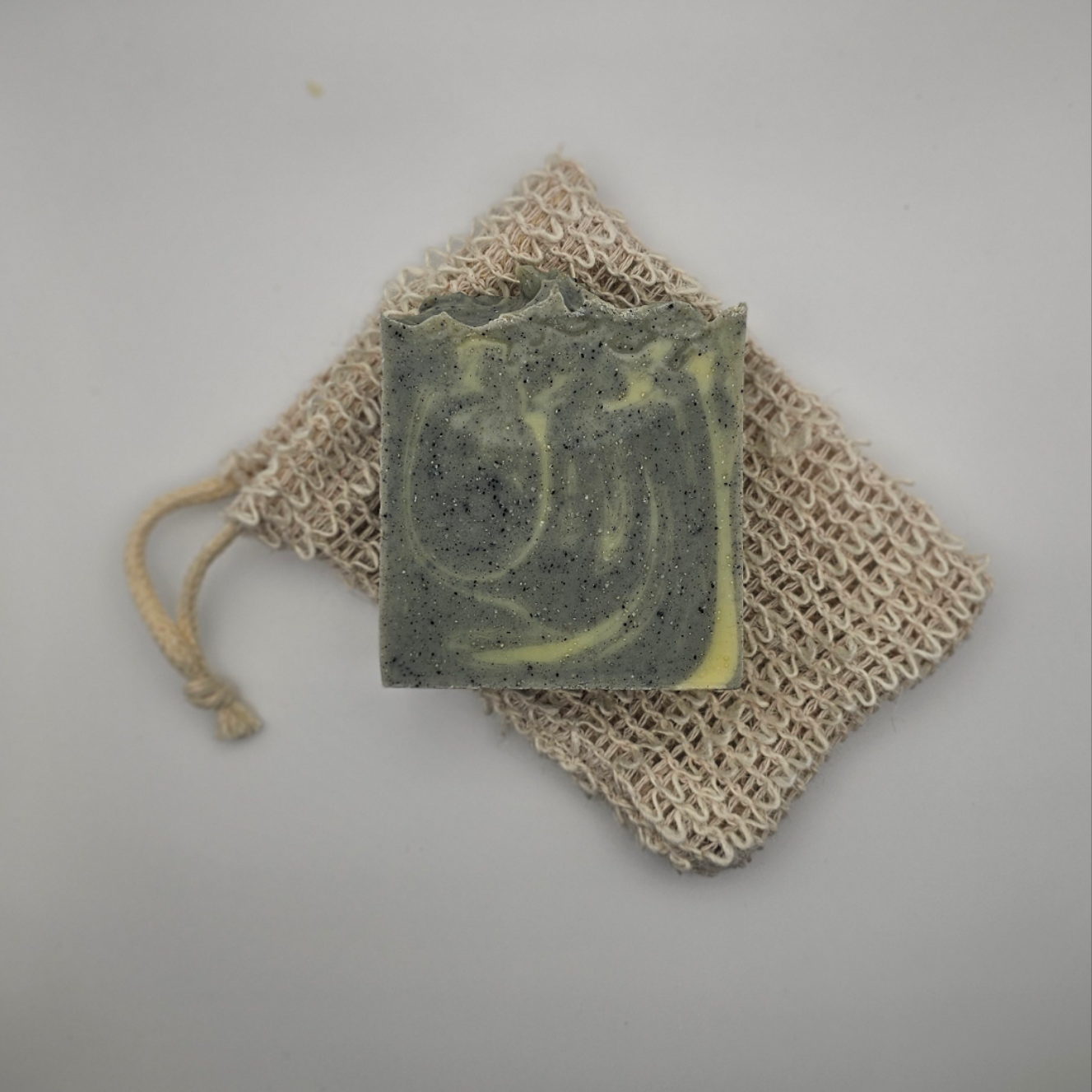 Starry Night tallow soap bar resting on hemp soap saver bag – calming lavender and cedarwood soap on grey background