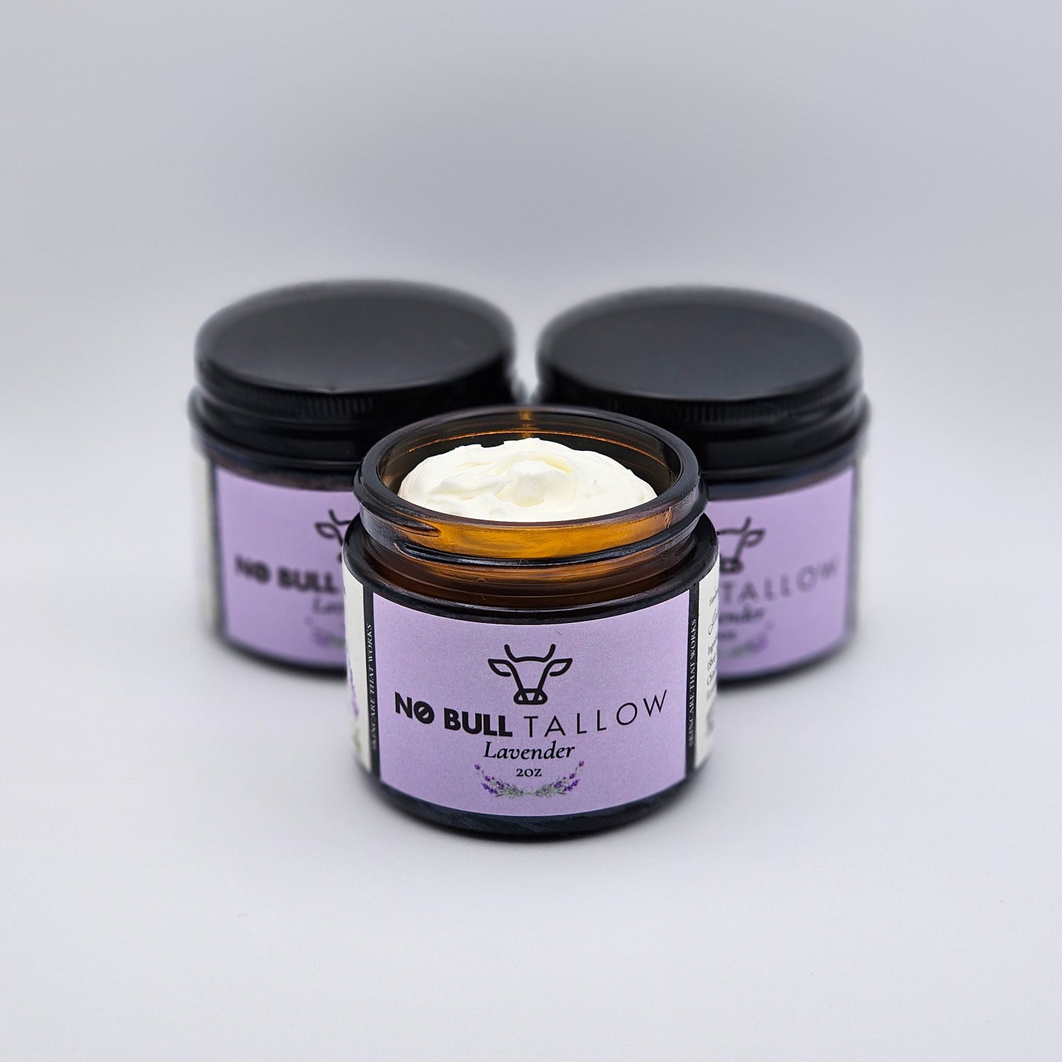Three purple jars with of lavender body butter on a white background